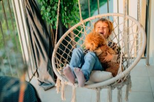 Little kid hugging a poodle dog at home on the balcony in spring